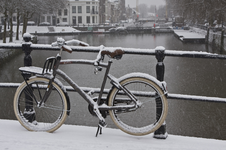 844959 Afbeelding van een besneeuwde fiets op de Zandbrug te Utrecht, met op de achtergrond de Weerdsluis.